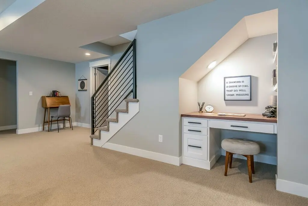 basement rec room with home office desk underneath the stairs