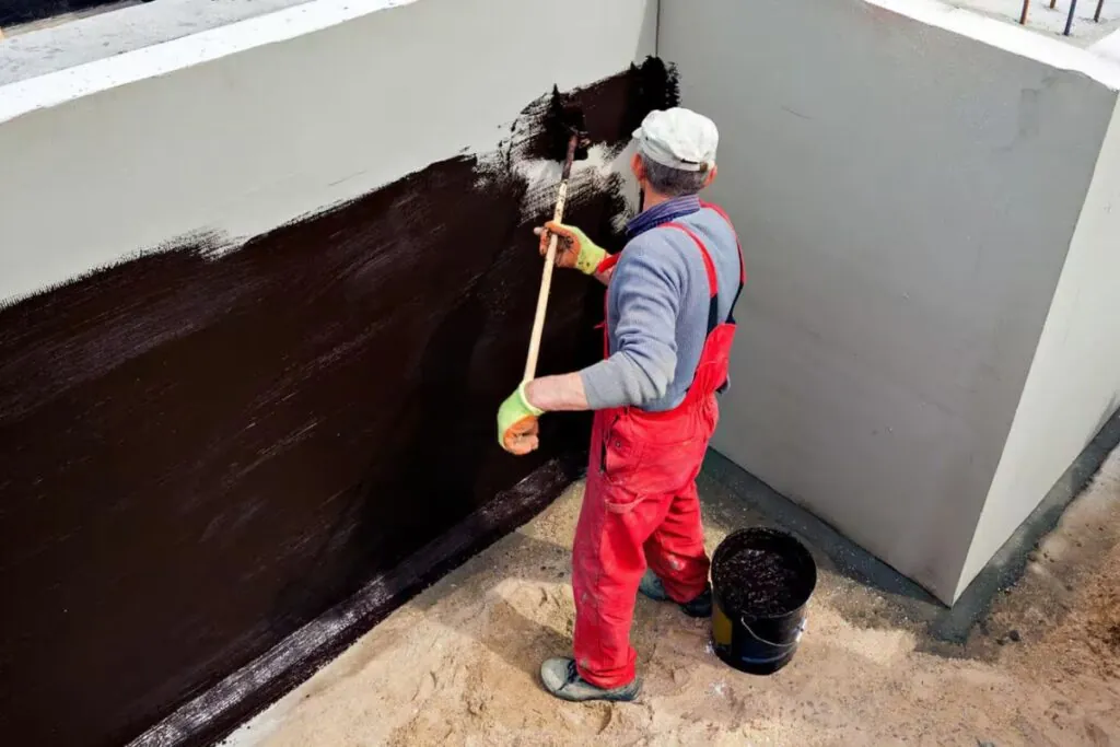 contractor applying waterproof in basement wall